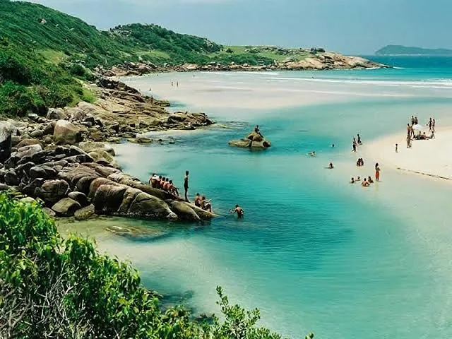 Rio e praia da Guarda do Embaú com águas verdes e pedras, perto da Pinheira
