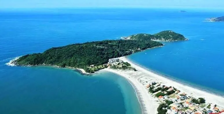 Vista aérea da Ponta do Papagaio com a faixa de areia e o mar azul, em Palhoça